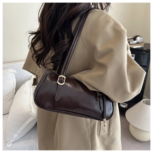 Détail du sac baguette en cuir brillant marron foncé avec boucle métallique dorée chic