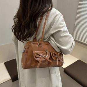 Brown bowling shoulder bag with dual front flap pockets and tassel bow decoration