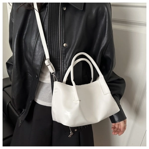 Detail of white leather bucket bag with adjustable strap worn by model in leather jacket