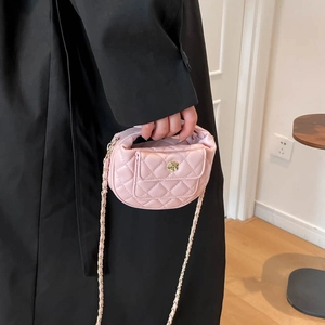 Pink quilted crossbody bag with gold flower clasp and chain strap held by model
