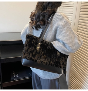Detailed back view of model wearing a black faux fur tote bag with leather strap
