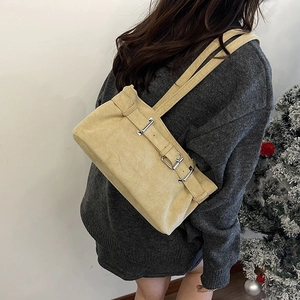 Sac baguette vintage en daim beige porté avec un pull en maille gris foncé