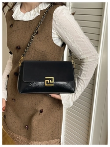 Detail of vintage black patchwork handbag with gold metal lock and chain strap