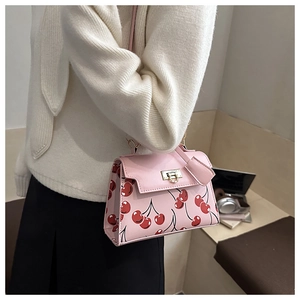Detail of pink shoulder bag with cherry print and golden twist lock closure
