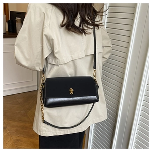 Detail of black leather crossbody bag with gold twist lock and chain strap