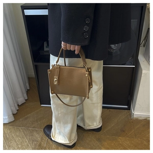 Detailed view of a brown leather handbag with gold hardware in a modern home setting