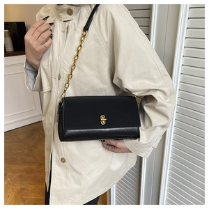 Detail of a chic black shoulder bag featuring a glossy finish and a gold twist-lock closure