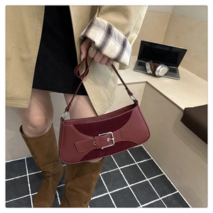 Detail of burgundy baguette bag featuring matte leather and suede texture with silver buckle