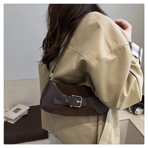 Detail of vintage brown shoulder bag with mixed leather textures and silver buckle on model