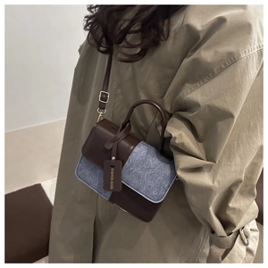 Détail d'un sac à main en cuir marron et tweed gris porté avec un trench-coat kaki