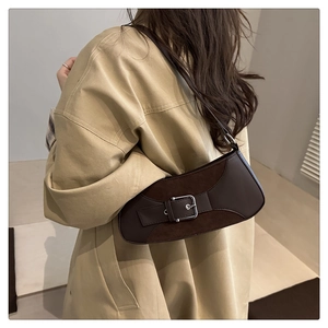 Detail of dark brown leather underarm bag with silver square buckle worn with beige coat