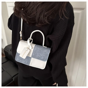 Detail of blue denim and white leather patchwork handbag with gold hardware