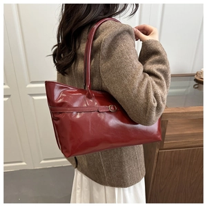 Deep red patent leather tote bag styled with a brown blazer for a chic office commute