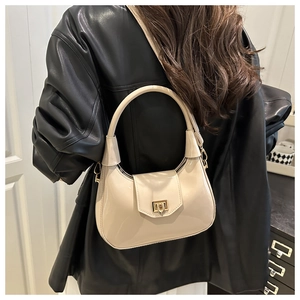 Detail of cream patent leather hobo bag with a gold square clasp and versatile side hooks