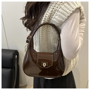 Detail of dark brown patent leather crescent bag with golden metal buckle clasp