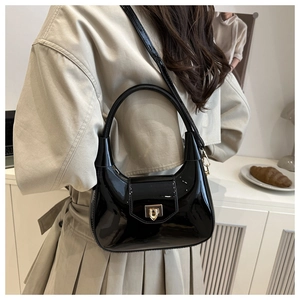 Detail of black patent leather handbag featuring a secure gold metallic twist-lock closure