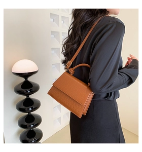 Detail view of brown crocodile texture on a chic rectangular handbag with adjustable strap