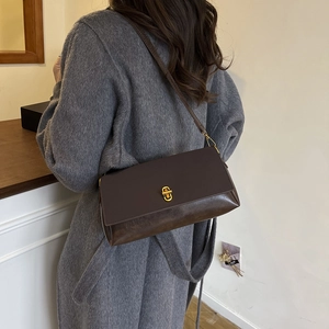 Brown leather crossbody flap bag for women styled with a winter coat in a cozy room
