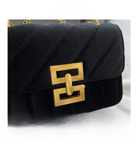 Close-up of black velvet shoulder bag featuring luxury gold geometric chain buckle detail