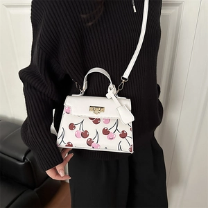 White cherry print handbag with gold turn-lock and detachable strap for winter 2025