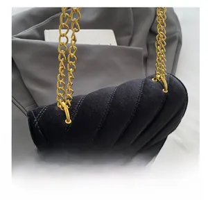 Detailed close-up of velvet crossbody bag featuring V-shaped quilting and gold metal buckle