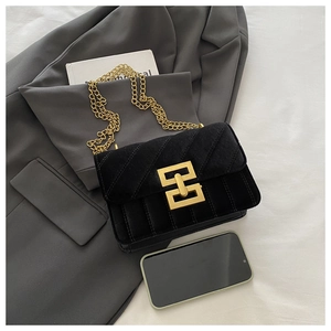 Close-up of black velvet quilted crossbody bag with gold chain strap and smartphone