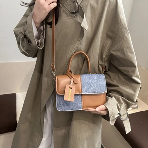Sac à main chic en cuir marron et denim bleu porté par un mannequin en trench-coat élégant