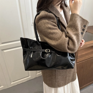 Glossy black patent leather tote bag styled with a professional urban outfit