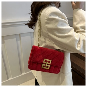 Close-up of red velvet shoulder bag featuring gold chain and geometric twist lock