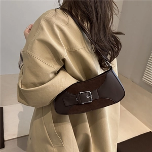 Dark brown leather baguette shoulder bag with silver buckle worn by a model in a beige trench