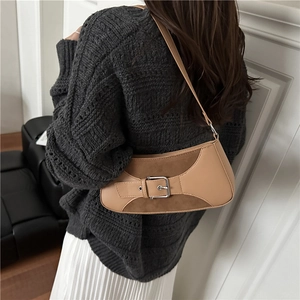 Brown leather underarm bag with silver buckle strap shown on model shoulder