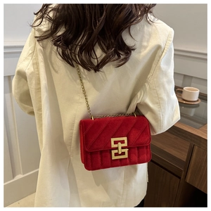 Detail of red velvet shoulder bag with large golden geometric clasp and chain strap