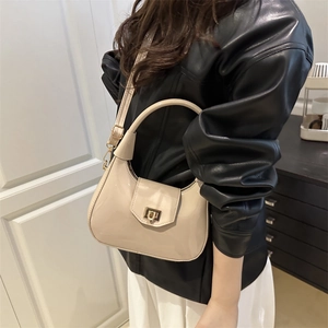 Minimalist beige patent leather hobo bag with gold buckle shown on a model