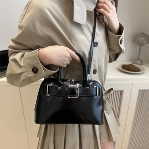 Glossy black leather crossbody bag with silver buckle and top handles for winter style