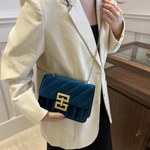 Navy blue velvet crossbody bag with V-quilted pattern and gold chain on model