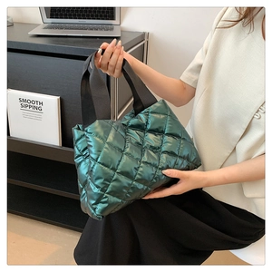 Macro detail of dark green quilted puffer tote bag with glossy finish and black strap