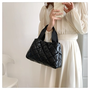 Detail of black quilted puffer tote bag with glossy finish and rhombic embroidery pattern