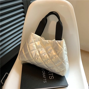 Detailed shot of silver quilted puffer tote bag on a modern chair with a chic metallic finish