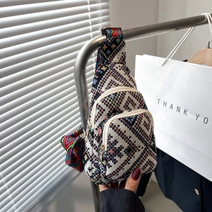 Detailed view of bohemian crossbody bag with woven geometric patterns and multi-zip compartments