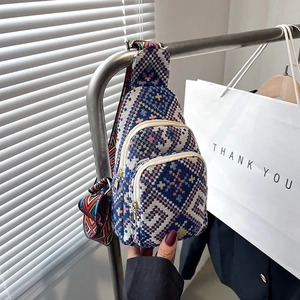 Detailed view of woven crossbody bag showing three zipper pockets and geometric strap