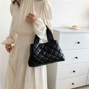 Quilted black tote bag with diamond pattern shown on model in white dress