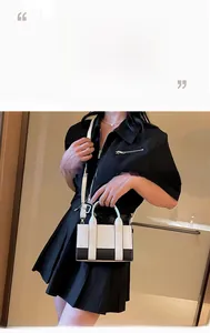 Detail of a contrast color mini square bag featuring black and white panels and a long strap