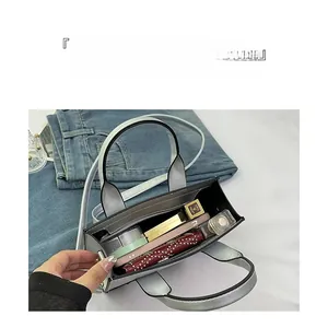Top view of silver tote bag showing spacious interior with cosmetics and a smartphone
