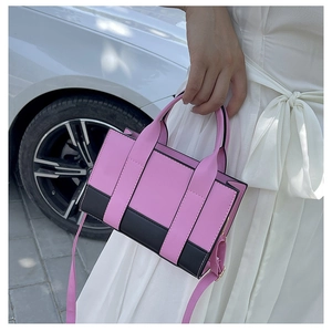 Detail of pink and black color-block structured handbag with dual top handles and strap