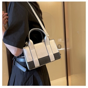 Detail view of a silver metallic crossbody bag with black trim on a female model