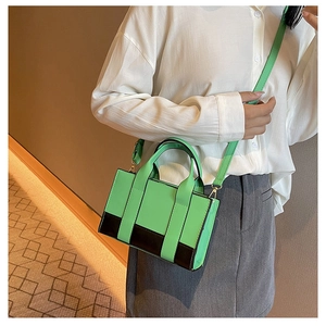 Detail of green and black contrast handbag with light gold hardware and PU leather finish