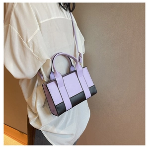 Detailed side view of lavender and black color-block PU leather crossbody bag on model