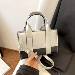 Detail view of the silver and black contrast stitching and gold metal hardware of the bag