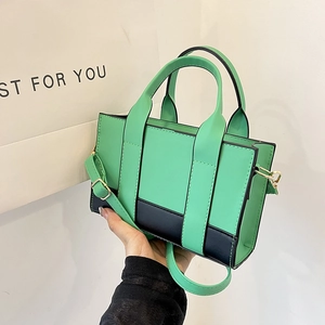 Detail of color-block tote bag in green and black leather with golden hardware