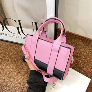 Detail of pink and black contrast tote bag with top handles and detachable shoulder strap
